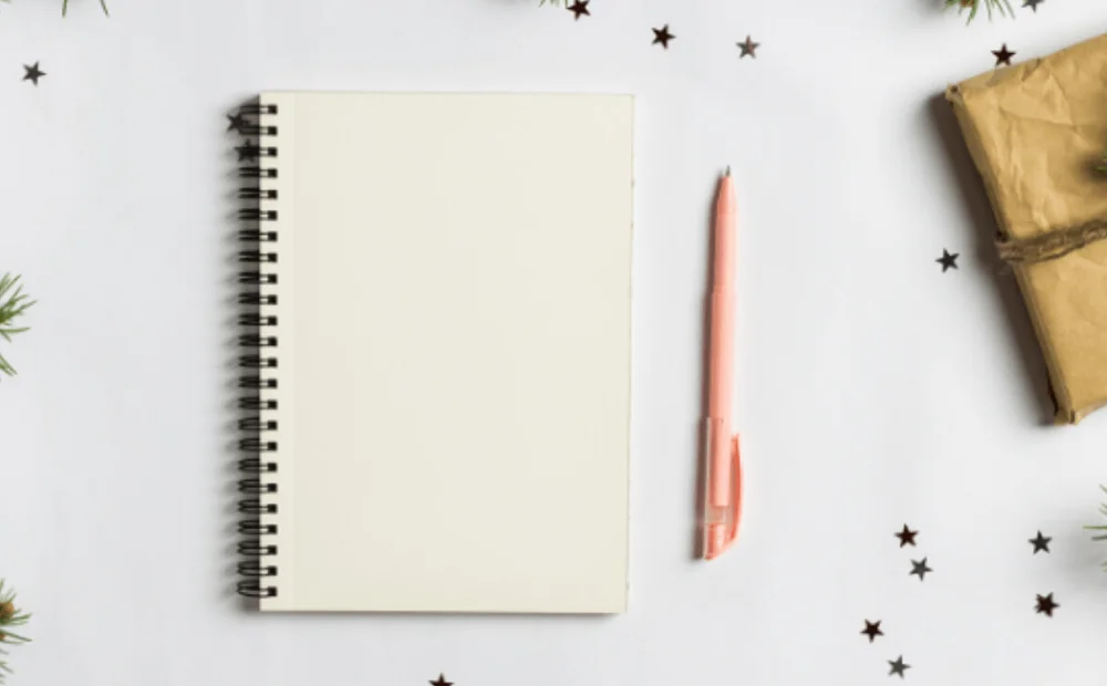 a notebook and pen with christmas branches around it a notebook and pen with christmas branches around it