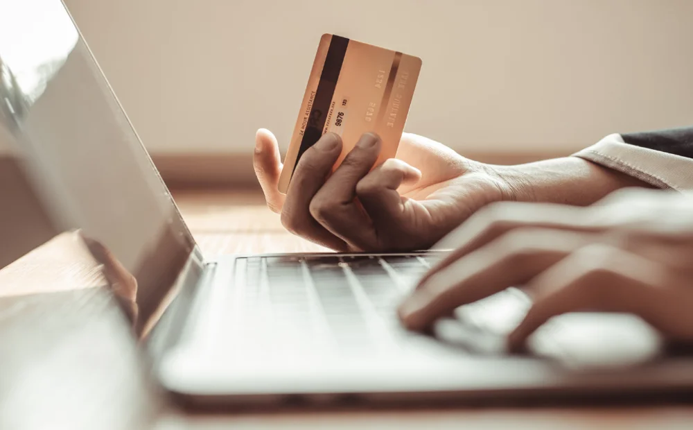 person typing on laptop and holding credit card person typing on laptop and holding credit card