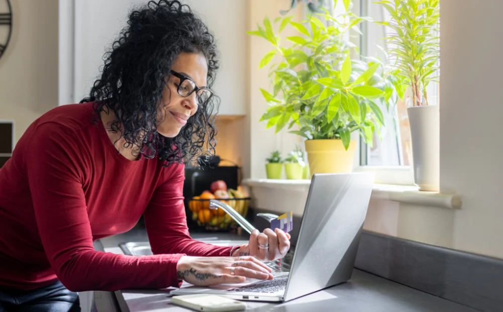 woman looking at her credit card with her laptop woman looking at her credit card with her laptop