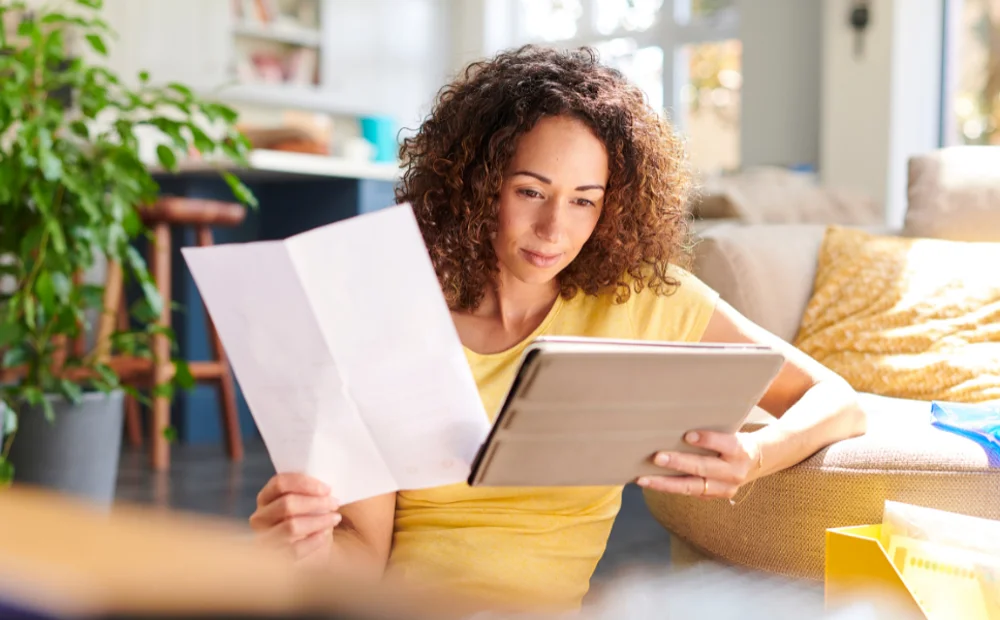 woman sat in front of sofa with papers and tablet woman sat in front of sofa with papers and tablet