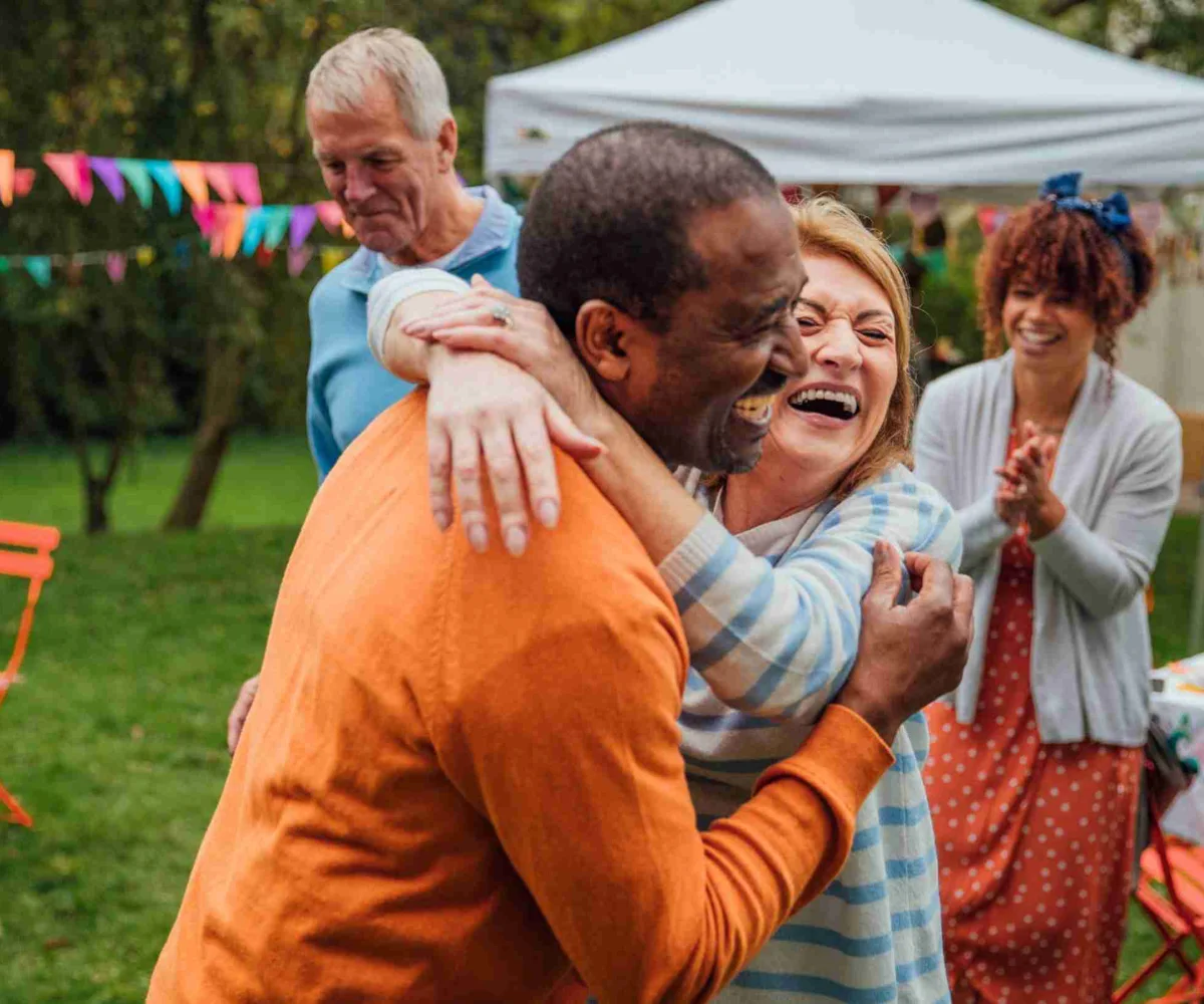 Women And Man Hugging And Laughing At Party