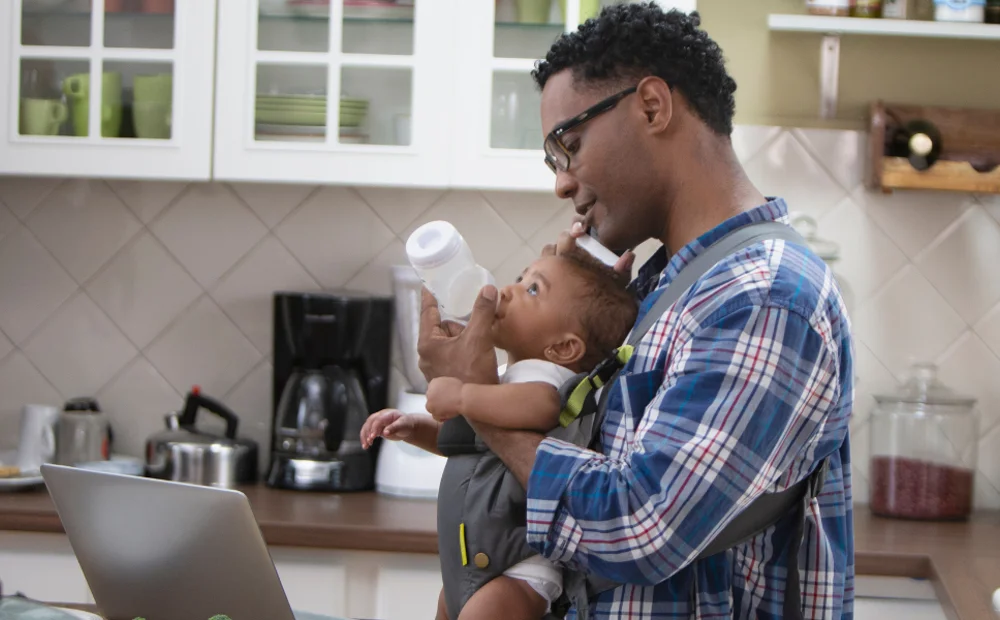 man bottle feeding baby strapped on his chest man bottle feeding baby strapped on his chest
