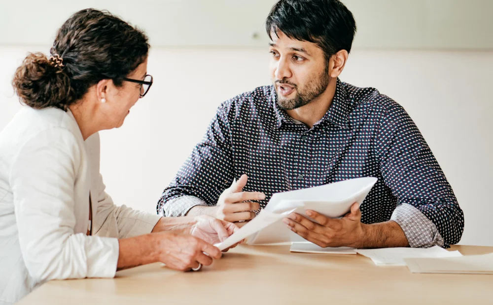 two people discussing holding a piece of paper two people discussing holding a piece of paper