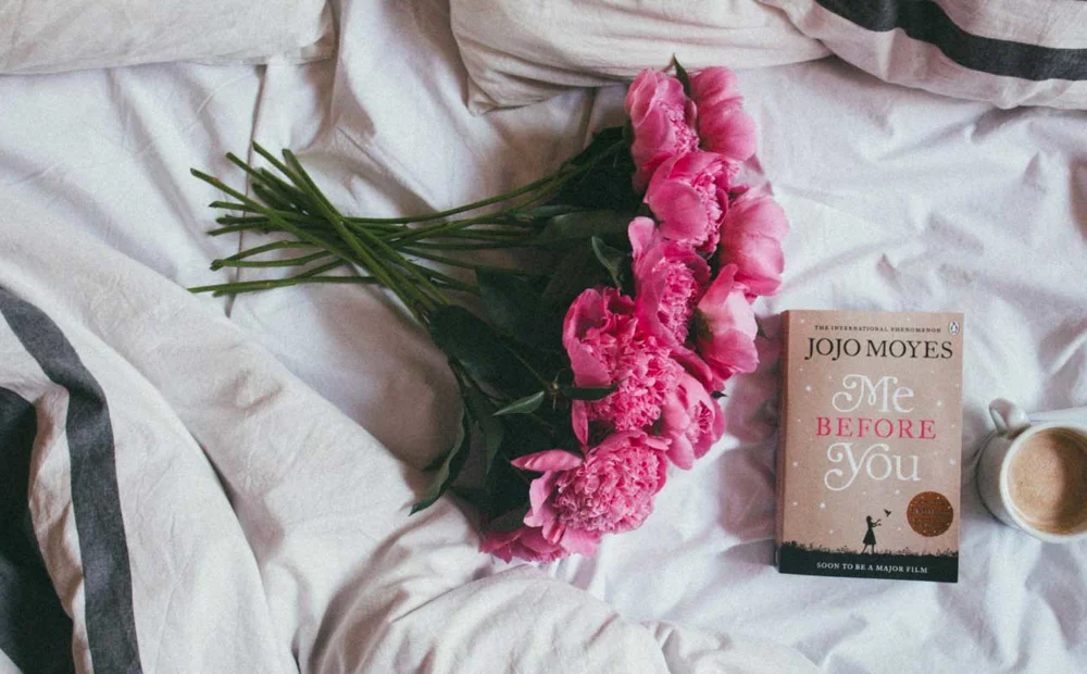 bouqet of flowers, book and cup of coffee on bedding bouqet of flowers, book and cup of coffee on bedding
