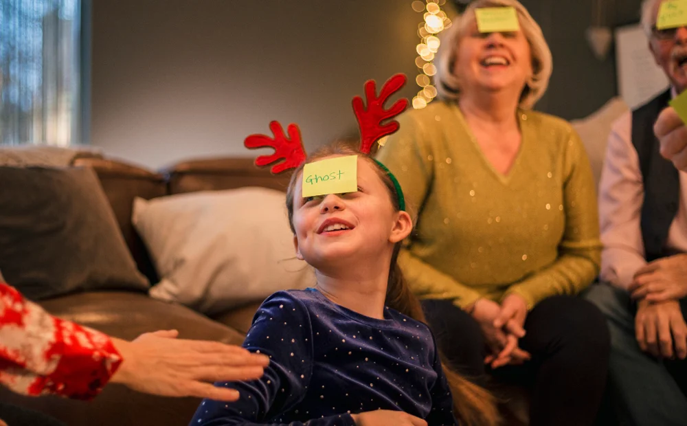 family with reindeer antlers playing games with sticky notes on forehead family with reindeer antlers playing games with sticky notes on forehead