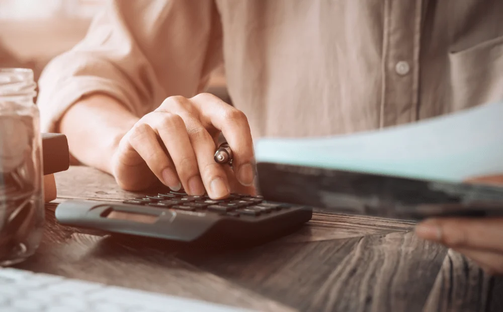 person using a calculator holding paper and pen person using a calculator holding paper and pen
